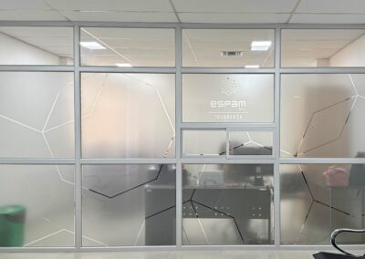 Oficinas de ESPAM MFL con vinil esmerilado decorativo y señalización de Tesorería en mamparas de vidrio.