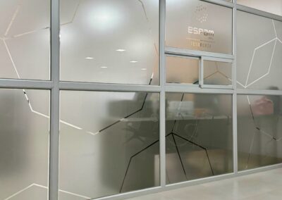 Mamparas de vidrio con vinil esmerilado geométrico y señalización de Tesorería en oficinas ESPAM MFL.