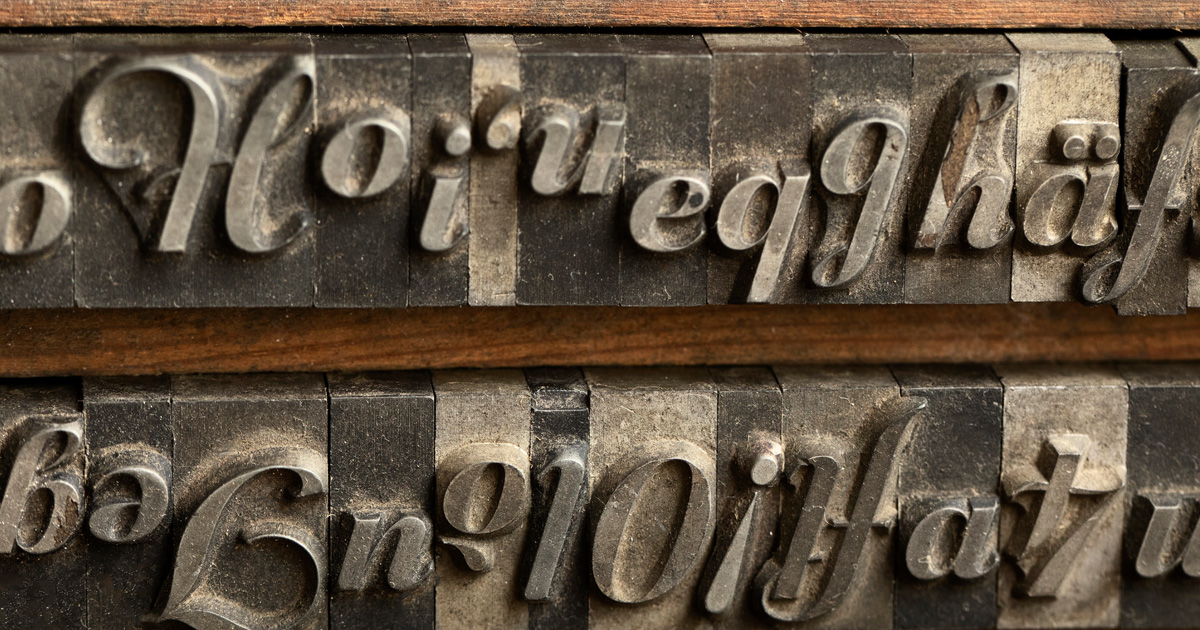 Primer plano de letras de metal de imprenta tipográfica antigua en una bandeja de madera